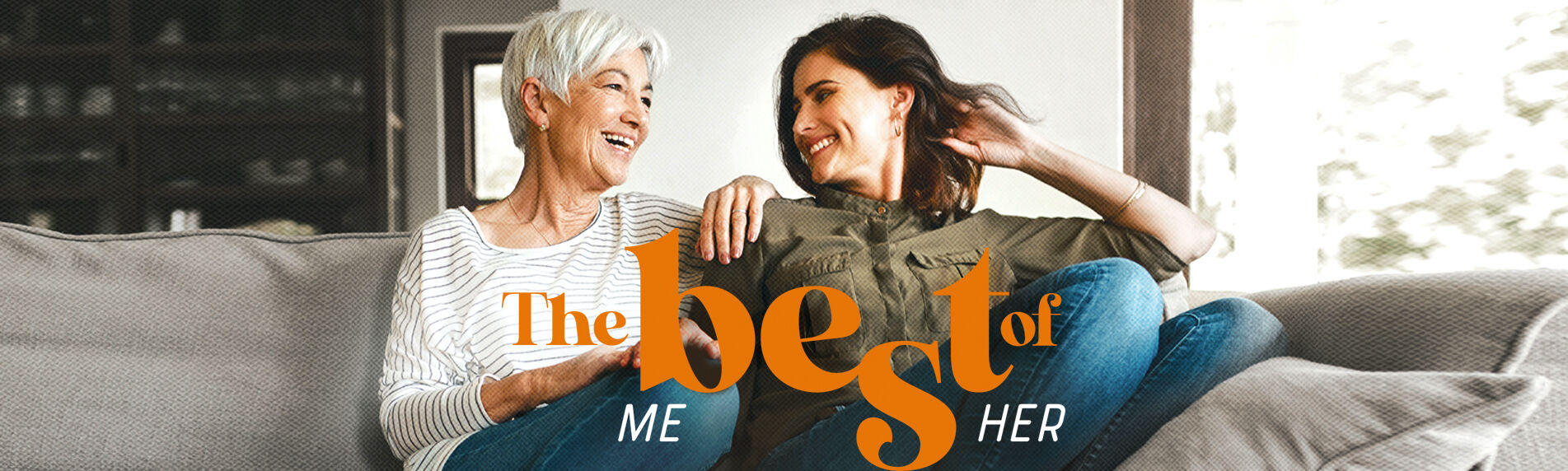 Mother and daughter sit on couch smiling at each other. 